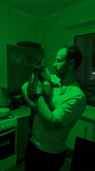 Man holds cat in kitchen with changing colored lights