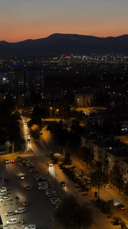 Konya at dusk, city lights coming on beneath a mountain horizon