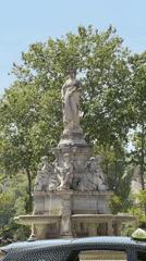 Taxi parked by fountain in Lyon under sunny skies