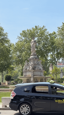 Taxi parked by fountain in Lyon under sunny skies