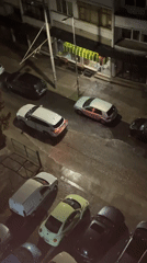 Heavy rainfall floods urban street, cars navigate water-covered roads