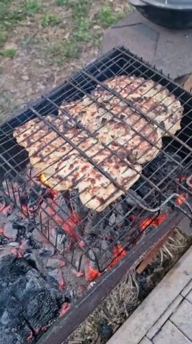 Person grills chicken over charcoal in Otchor, Russia