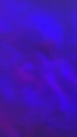 This is a close-up, vertical video with no discernible people or objects. The background is a blur of shifting purple and pink hues, resembling abstract clouds or a light effect. The colors blend and transition smoothly throughout the short clip. There is no discernible action or interaction.