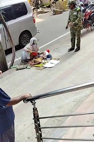 Woman tends to baby on Dhaka sidewalk