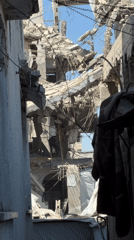 Inside a collapsed Gaza building, two people work through rubble