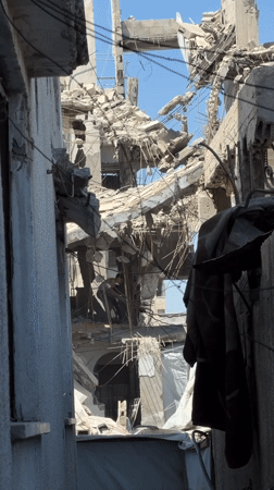 Inside a collapsed Gaza building, two people work through rubble