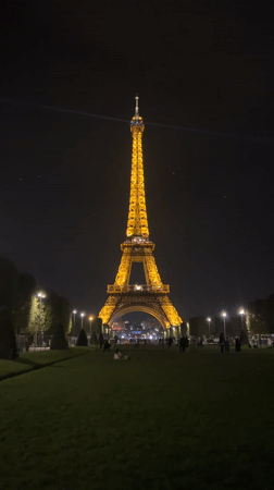 Evening visitors gather at illuminated Eiffel Tower in Paris