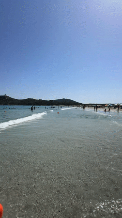 Sardinian beach afternoon: clear water, sailboats, and summer crowds