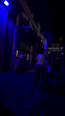 Late-night dancing and a curious cat under blue lights in San Juan
