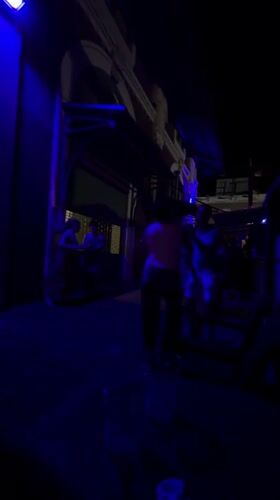 Late-night dancing and a curious cat under blue lights in San Juan