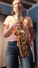 Woman plays saxophone indoors in Viadana, cat watches