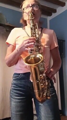 Woman plays saxophone indoors in Viadana, cat watches