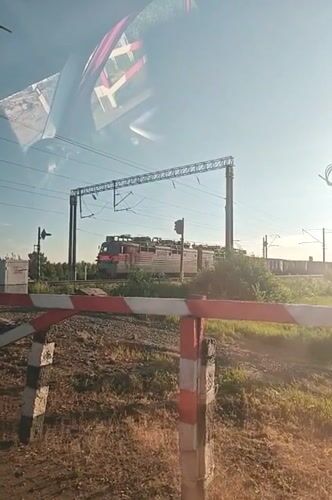 Freight train passes through Kambarka, Russia behind railway barrier