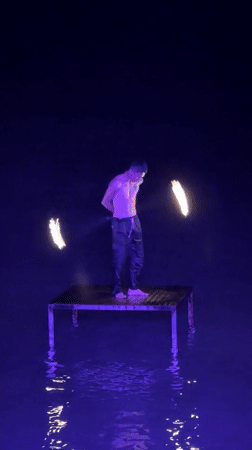 Fire dancer spins torches on a water platform in Koh Samui