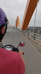 Scooter rider crosses bridge in Vietnam under overcast skies