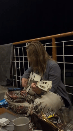 Woman plays acoustic guitar on porch in Haini