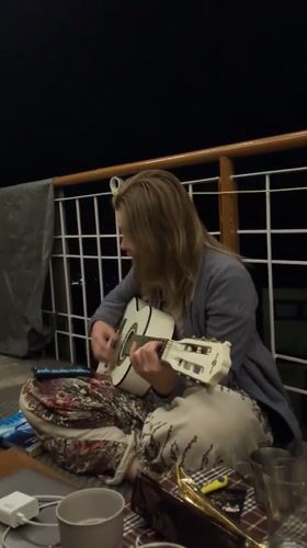 Woman plays acoustic guitar on porch in Haini