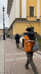 Man in orange jacket walks Saint Petersburg sidewalk
