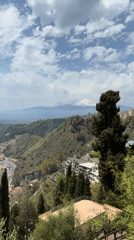 Street musician performs in Taormina with Mount Etna backdrop