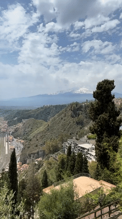 Street musician performs in Taormina with Mount Etna backdrop