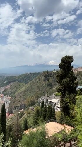 Street musician performs in Taormina with Mount Etna backdrop