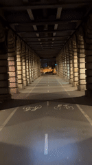 Cyclist navigates illuminated Paris tunnel at night
