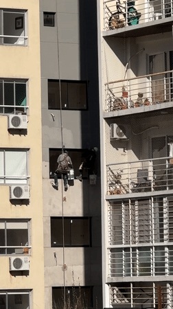 Building maintenance workers rappel down Buenos Aires facade
