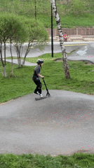 Child rides scooter on pump track wearing safety gear