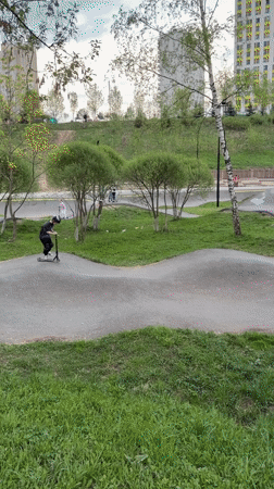 Child rides scooter on pump track wearing safety gear