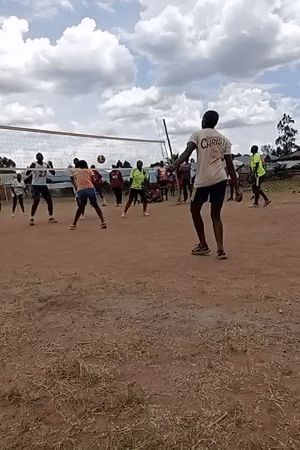 Young adults play volleyball on dirt court in Kenya