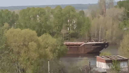 Woman photographs river cruise ships and barges from waterfront location
