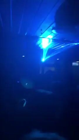 Here's a concise description of the video:

The video shows a group of people dancing at a club. The lighting is primarily dark, with bright, colorful lasers flashing across the room in shades of green, purple, and blue.  The crowd is dense, and the individuals are mostly silhouetted against the light. The camera angle looks up at the ceiling and the light effects.