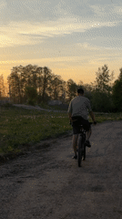 Cyclist rides rural road during sunset in Noviy, Russia