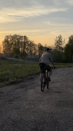 Cyclist rides rural road during sunset in Noviy, Russia
