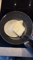 Woman cooks crepes in Khimki kitchen during morning routine
