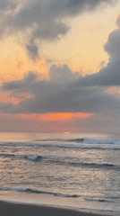 Dusk on a black sand beach in Blahbatuh, bonfire and sunset sky