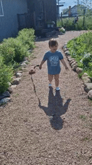 Child plays with pink toy on gravel path in Kempelevo