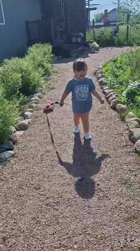 Child plays with pink toy on gravel path in Kempelevo