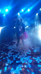 Wedding celebration features dancing couple, scattered money on floor