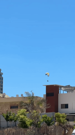 Paragliding over Netanya's modern skyline on clear afternoon
