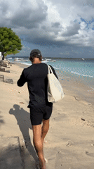 Man walks beach in Nusa Penida carrying bag