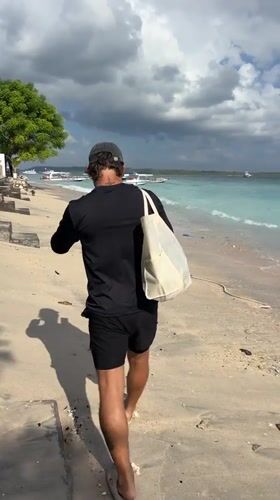 Man walks beach in Nusa Penida carrying bag
