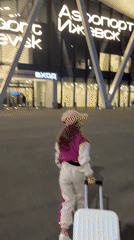 Girl with suitcase arrives at Izhevsk Airport during evening