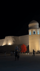 Evening gathering at illuminated Khiva fortress draws visitors and diners