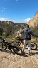 Man with dirt bikes overlooks valley near Melnik, Bulgaria