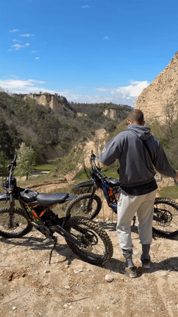 Man with dirt bikes overlooks valley near Melnik, Bulgaria