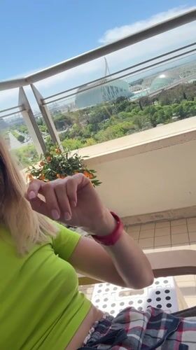 Woman enjoys balcony moment with orange tree in Valencia