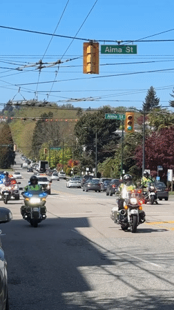 Police motorcade with flashing lights travels through downtown Vancouver