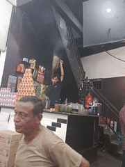 Man smokes cigarette inside small store in Kruet Teumpeun