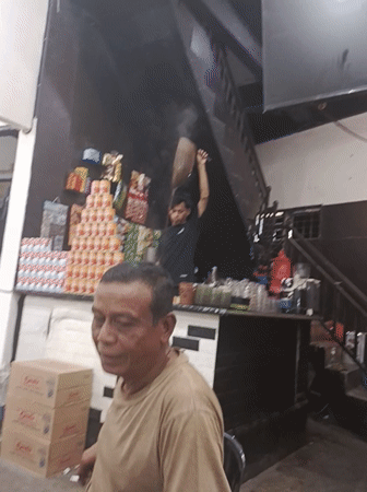 Man smokes cigarette inside small store in Kruet Teumpeun